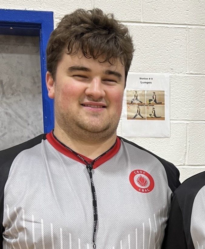 Daniel smiles at the camera, dressed in his grey referee's shirt and whistle.