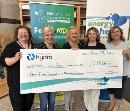 Three Hydro employees join 2 Kids Eat Smart representatives in front of two banners. They are holding a large presentation cheque from Hydro to Kids Eat Smart for $58,670.07