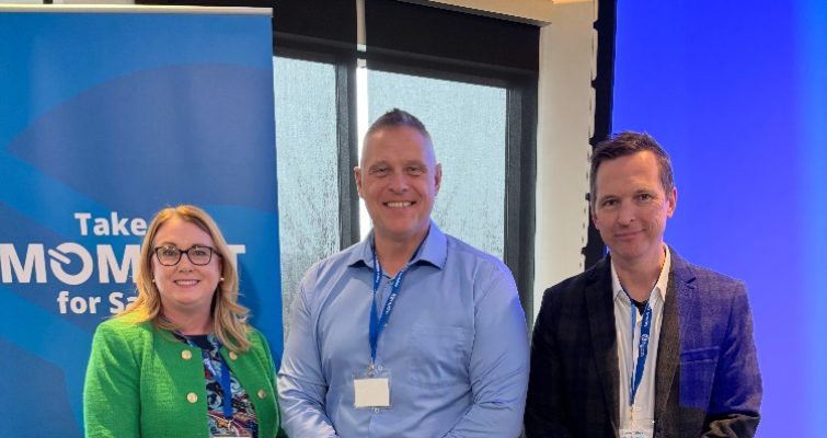 Jennifer Williams, Dan Comiskey and Steve Tilley, dressed in business attire and standing in front of a Hydro banner, smiling at the camera.