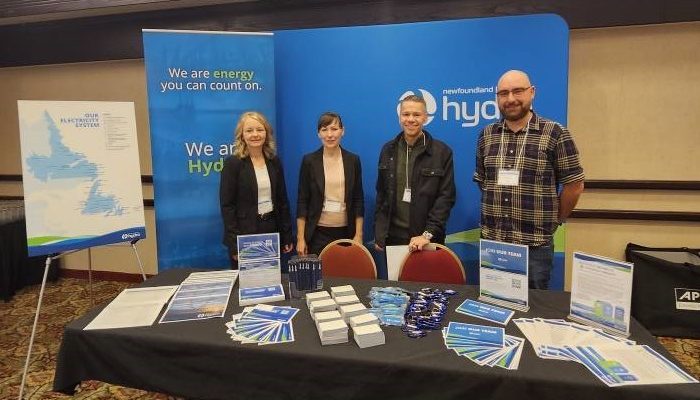 Four Hydro employees standing in front of a blue Hydro booth at the PPA Reverse Trade Show, smiling at the camera.